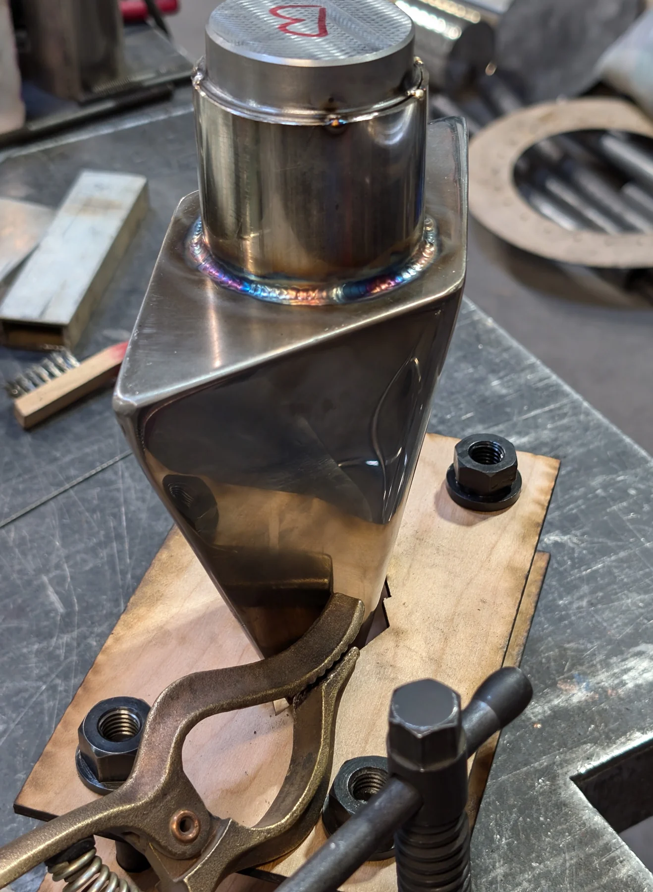 Close view of a clean welded stainless steel fabrication detail held in a fixture